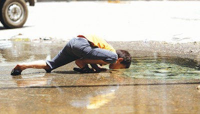 صورة مؤثرة..طفل سوري يشرب من المياه المتجمعة على أرضية الشارع