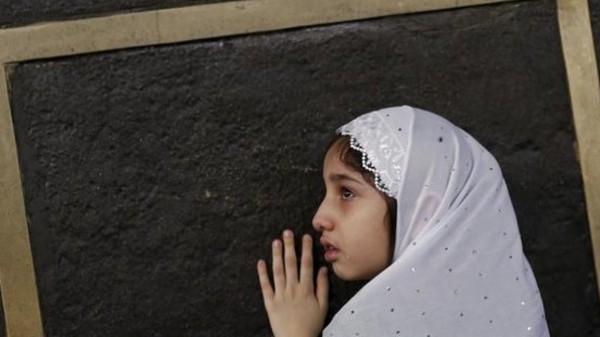 صورة لطفلة تتعلق بأستار الكعبة محاولة احتضانها
