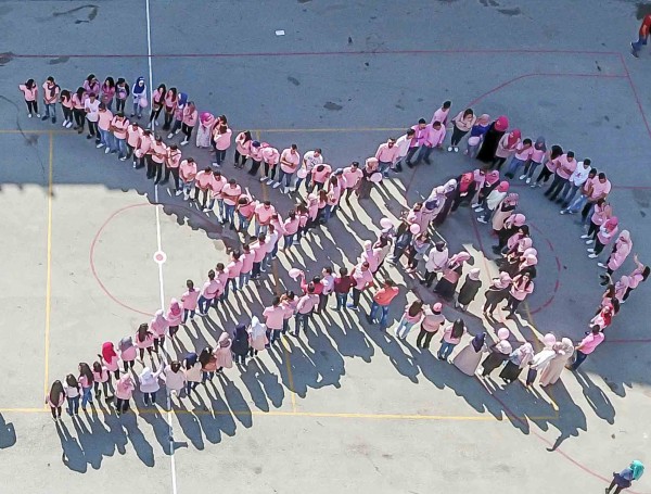 تشكيل أكبر شعار بشري للتوعية بسرطان الثدي في كلية فلسطين الاهلية