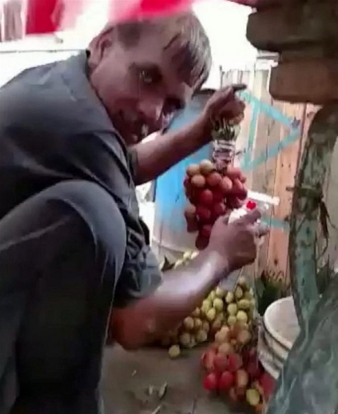 مشهد مرعب لبائع فاكهة يرش العنب باللون الأحمر