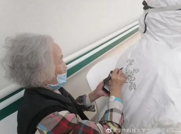مسنة صينية ترسم زهرة على بدلة ممرضة بعد شفائها من فيروس "كورونا"